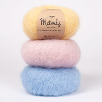 re gomitoli di lana DROPS Melody impilati, uno con etichetta del marchio.